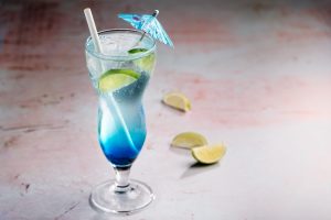 Kuvassa näkyy sininen jääkarhu-juoma, jossa on koristeena limejä, sekä sininen päivänvarjo.