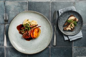 Kuvassa näkyy kairitsan kare annos, jossa on myös kasviksia, sekä leipä.