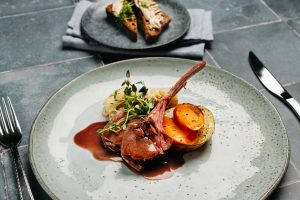 Kuvassa näkyy kairitsan kare annos, jossa on myös kasviksia, sekä taka-alalla leipä.