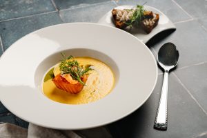 Kuvassa on savuinen lohikeitto lautasella leivän kanssa.